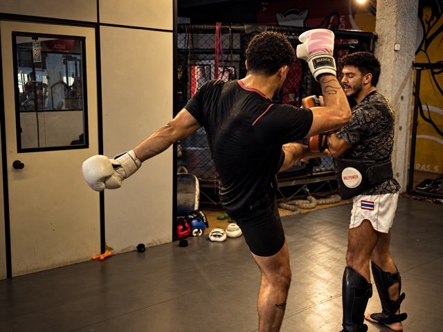 Aluno praticando chute em manopla durante treino no CT Uchiha